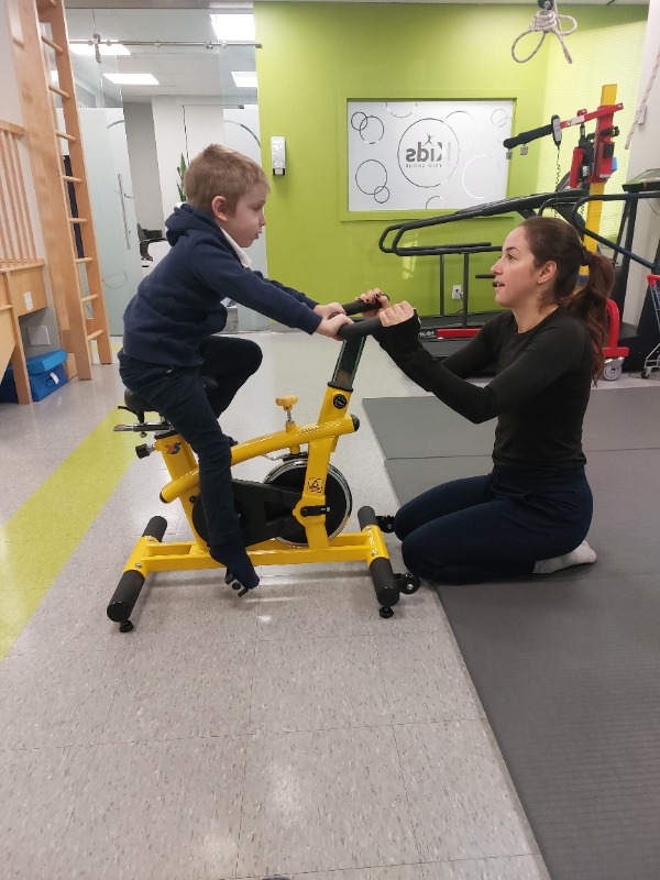 A physiotherapist working with a child on specialized physiotherapist equipment. The child is in a session to deal with their growing pains.