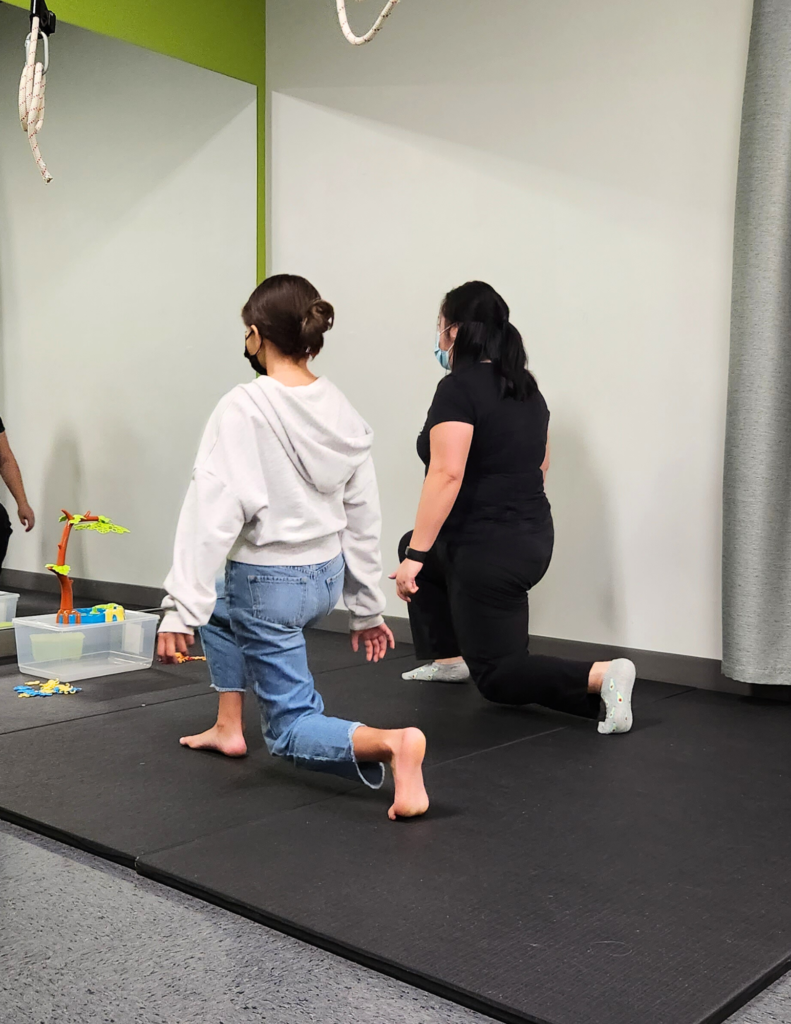 A physiotherapist from Kids Physio Clinic working with a client on Osgood-Schlatter’s Disease.