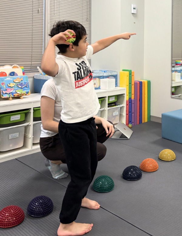 A child throwing a ball at a physiotherapist session at a Kids Physio Group clinic for little leage elbow